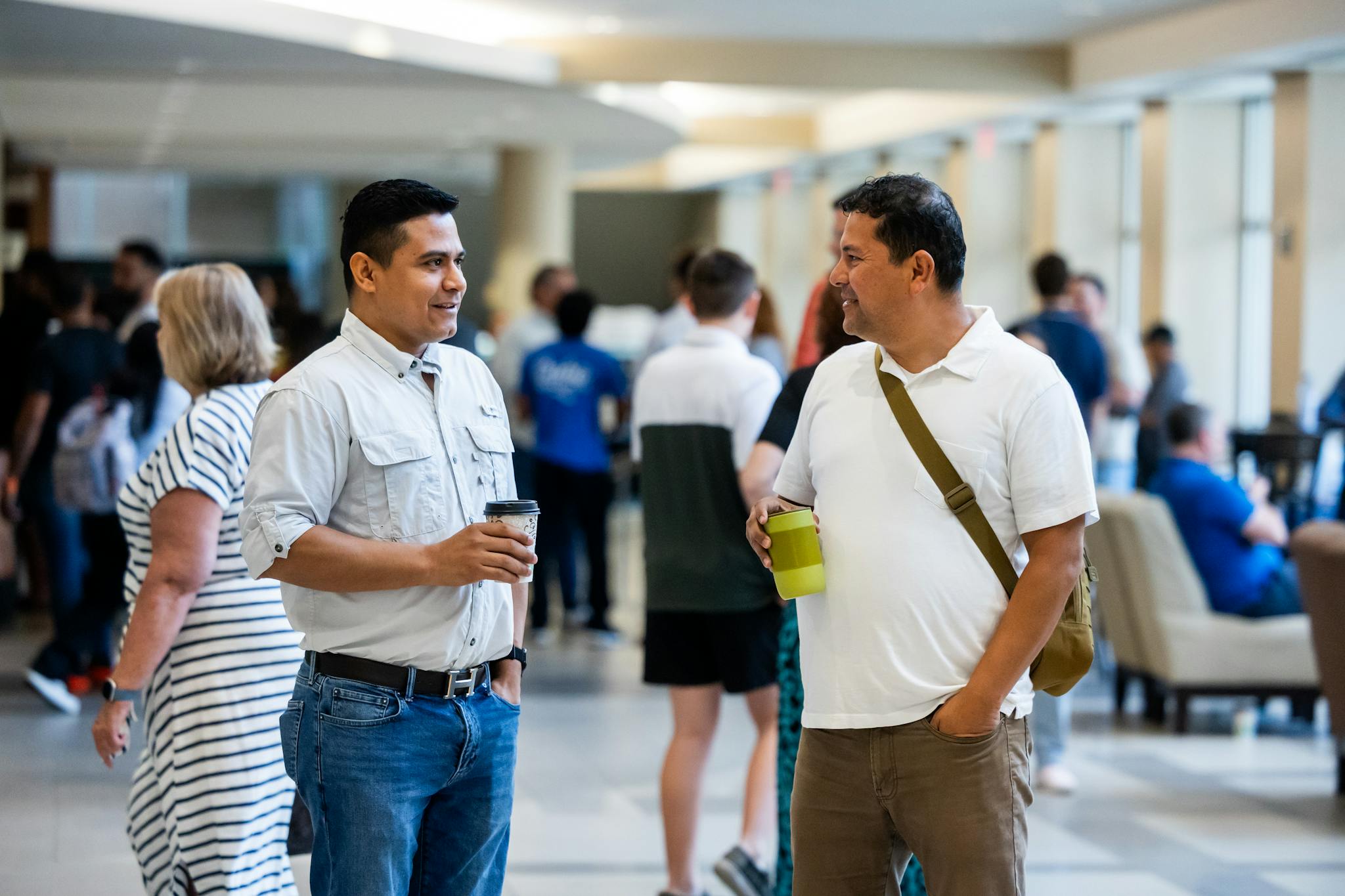 Two adults engaging in casual conversation during an indoor networking event.